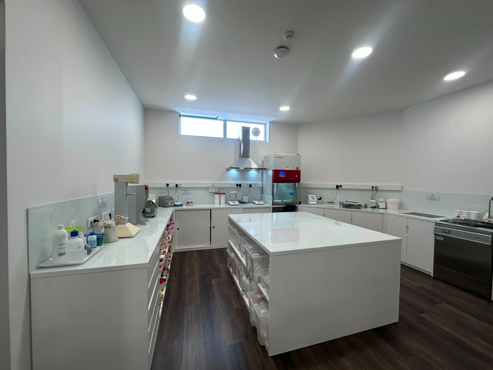 Vista do laboratório de manipulados, com bancada central e equipamentos de preparação